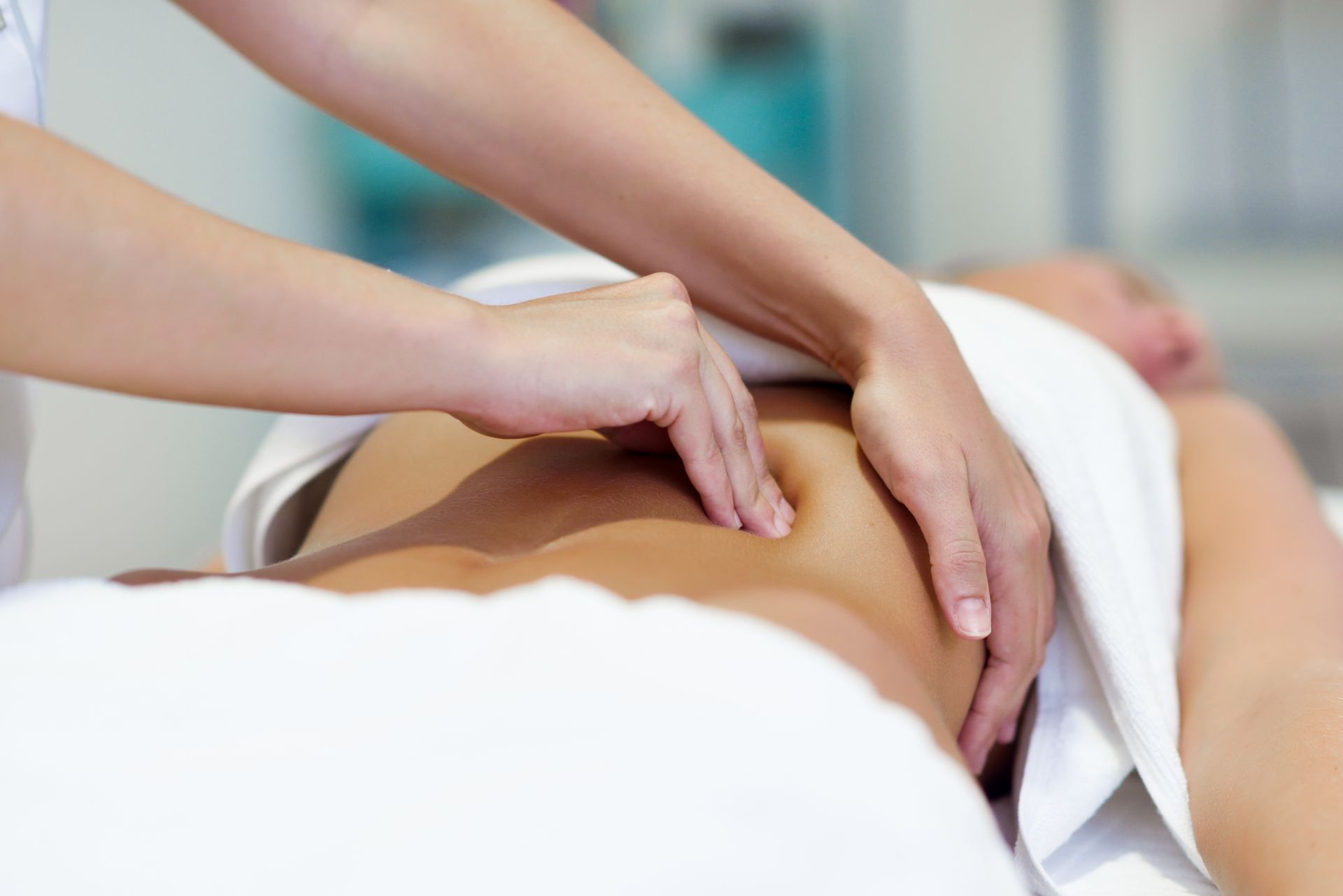 Female patient is receiving treatment by professional osteopathy therapist. Woman having abdomen massage in a physiotherapy center. Female patient is receiving treatment by professional osteopathy therapist. Woman having abdomen massage in a physiotherapy center.